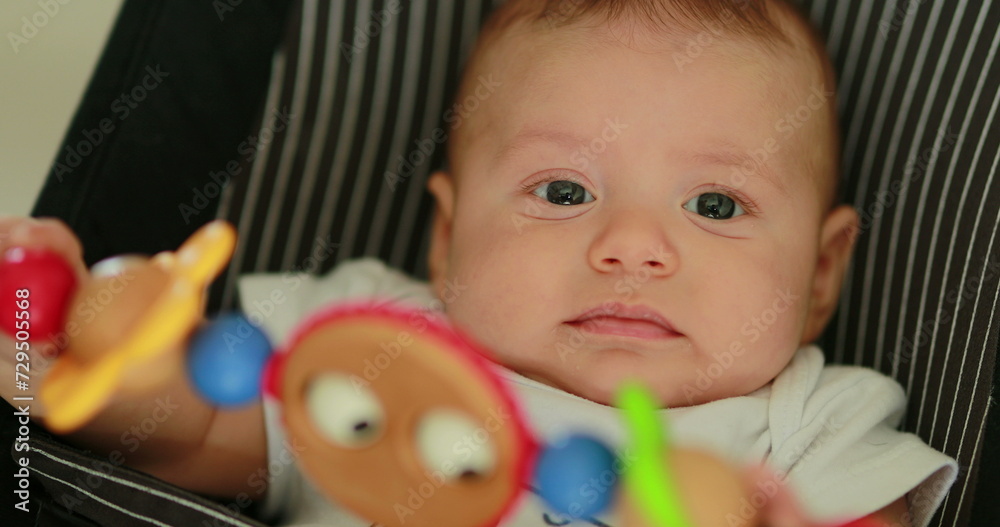 Baby newborn in chair seated with spinning toy in the foreground Baby newborn in chair seated with spinning toy in the foreground