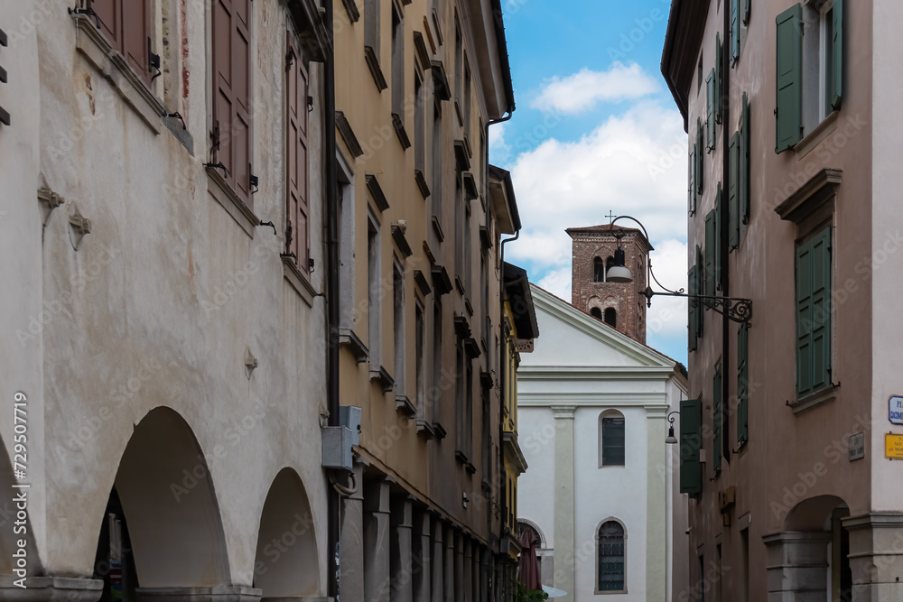 Stroll along narrow urban street that meanders towards magnificent ancient city center of charming town of Udine, Friuli Venezia Giulia, Italy, Europe. Urban tourism in historic northern Italian city