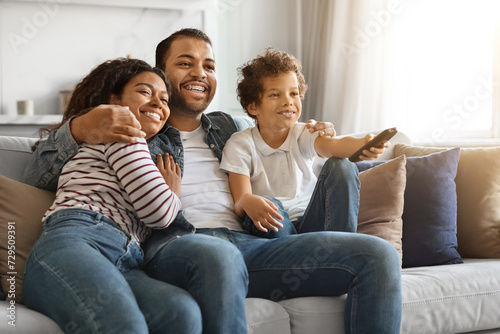 African american family of three cuddling and watching television together at home