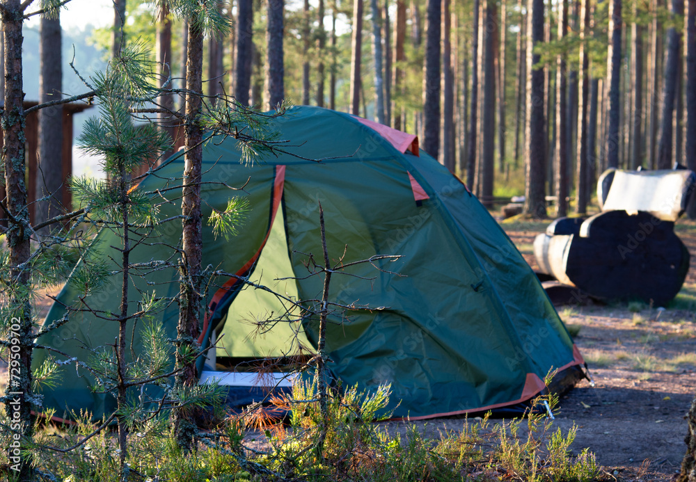 Tent in a tourist camp outdoors. A colorful tent stands in a green forest. Travel Tourism Tourism Leisure Active lifestyle.