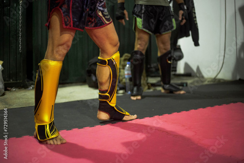 Powerful Muay Thai fighters' legs, shielded by shin guards, showcase strength and determination during an intense training session in the Thai martial art.