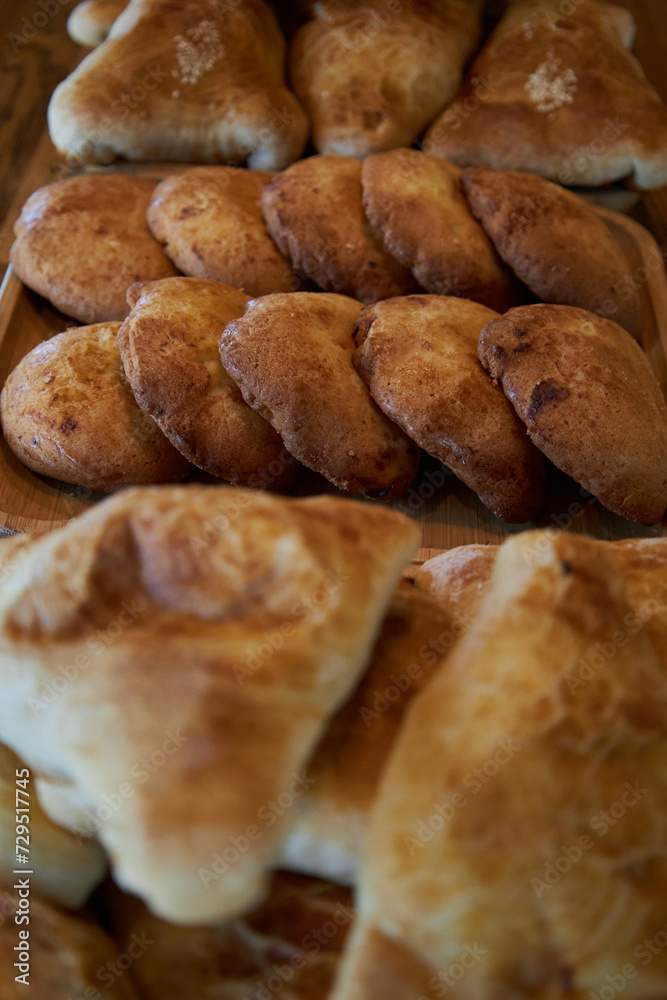 Fresh pastries on wooden plates: sochen sochnik sweet made from shortcrust pastry, cottage cheese filling and triangular samosas samosas with meat. national cuisine, Assortment of baked goods in cafe