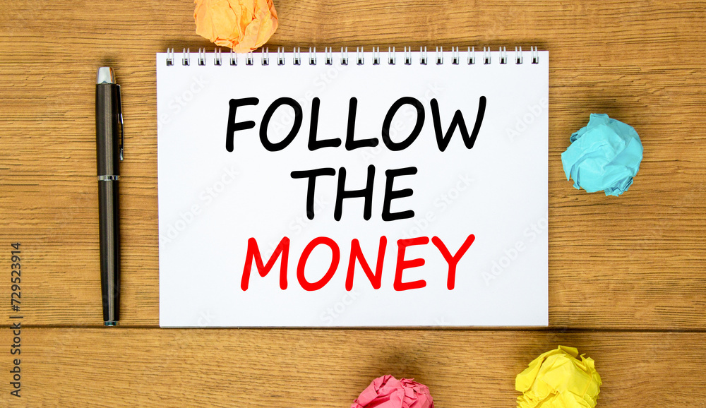 Naklejka premium Follow the money symbol. Concept words Follow the money on beautiful white note. Beautiful wooden background. Black pen. Colored paper. Business and follow the money concept. Copy space.