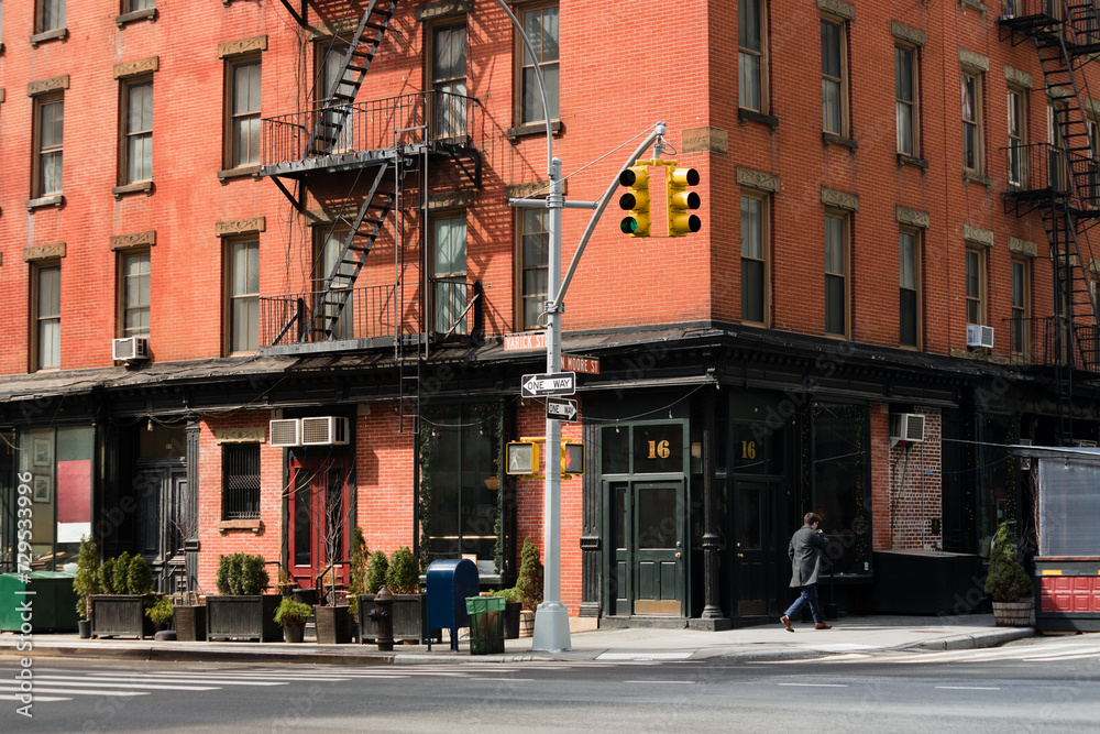 A beautiful corner view of an old building with a classic red brick wall facade and an iron fire escape in New York City