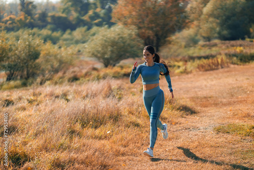 A confident young athletic woman running through an open grass field