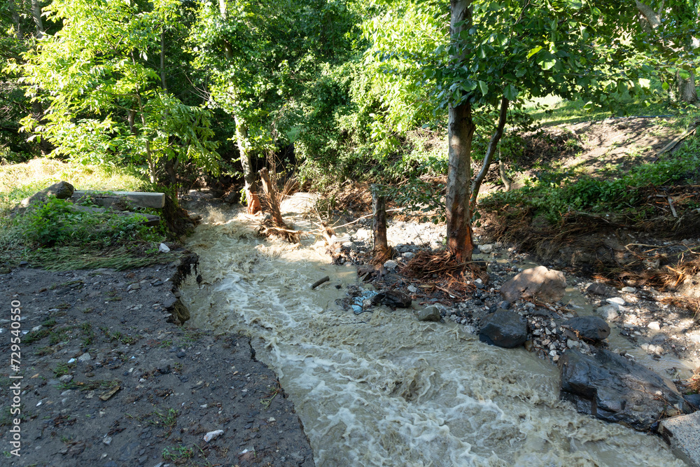 Fototapeta premium Dirty stream of a mountain river after rain and mudflow with soil erosion. Landslides and natural disasters concept