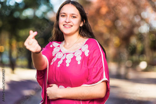 Young Moroccan woman doing heart love shape with hands with traditional dress. InspireInclusion