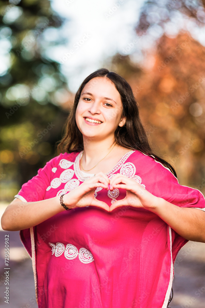 Young Moroccan woman doing heart love shape with hands with traditional dress. InspireInclusion Young Moroccan woman doing heart love shape with hands with traditional dress. InspireInclusion
