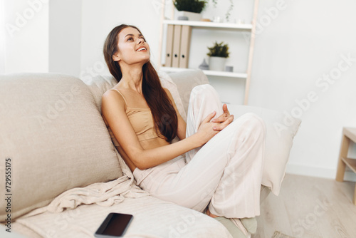 Cosy Home Bliss: Confident Woman Smiling on White Sofa in Modern Living Room © SHOTPRIME STUDIO
