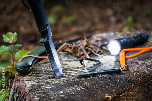 Several survival and bushcraft tools on a tree stump photo