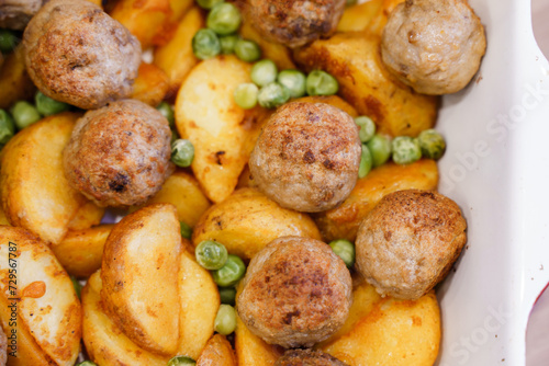 Delicious hot lunch from the oven potato slices, meatballs and green peas