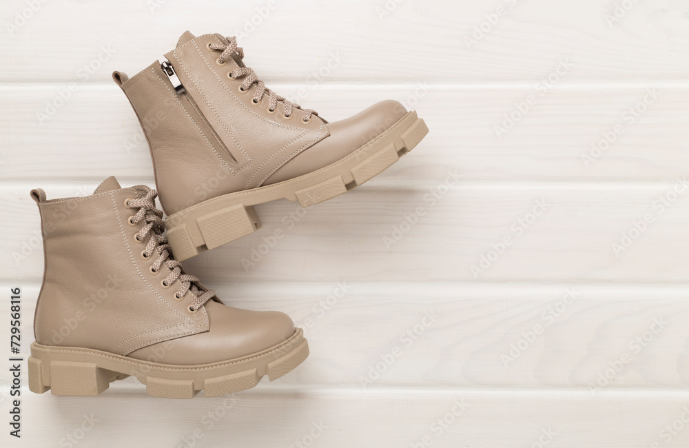 Beige trendy boots on wooden background, top view. Beige trendy boots on wooden background, top view.