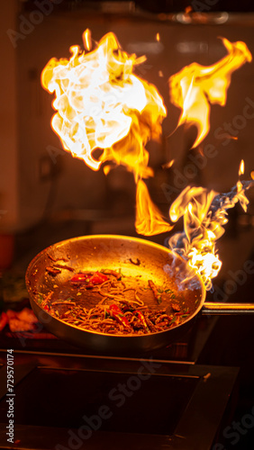 Chef preparing food on a frying pan with fire