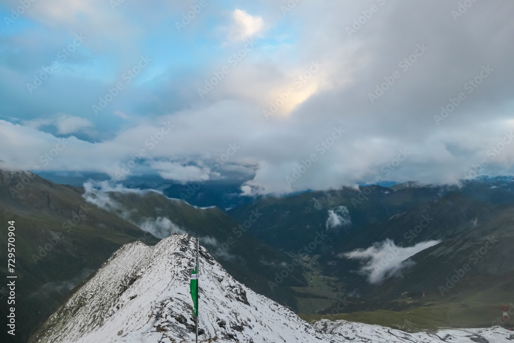 Panoramic view from mountain peak Arnoldhoehe in Ankogel Group, High Tauern National Park, Austria. Wanderlust in untamed snow covered Austrian Alps. Cloud covered terrain in idyllic hiking atmosphere