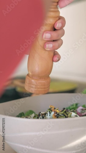 Woman's hand putting spices on a salad