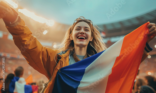 An excited female sports spectator holding a france flag in a sports stadium photo