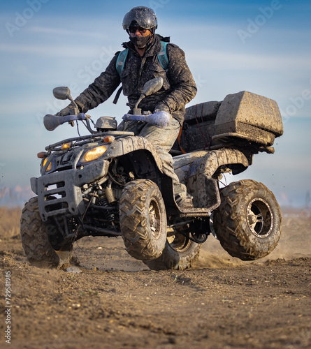 a man rides a quad on the sand on two wheels