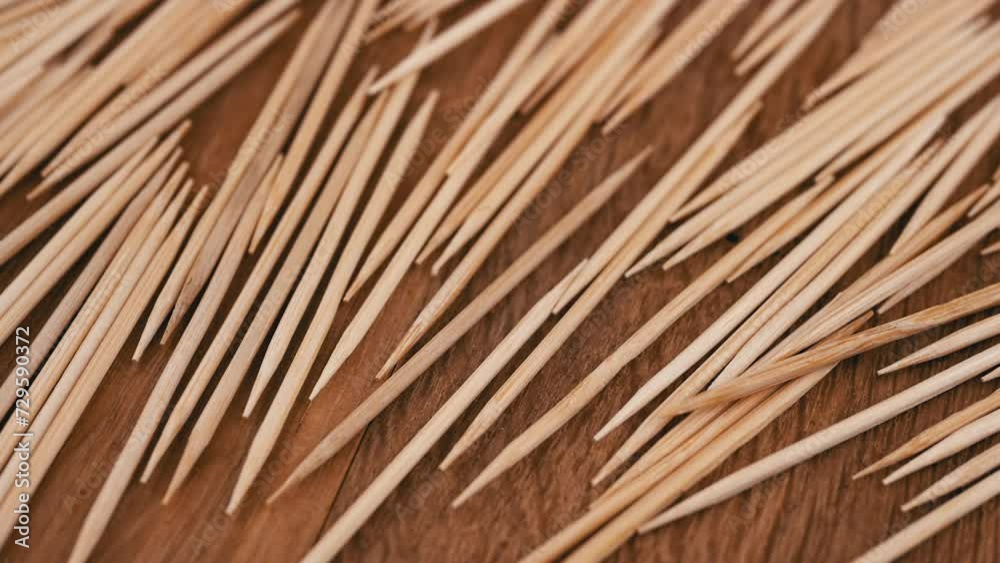 Lots of Scattered Brown Toothpicks Rotate on a Wooden Background. Close up. Top view. Texture of sharp bamboo wooden toothpicks. Home oral care after meals. Teeth cleaning. Blurred motion. Dentistry. Lots of Scattered Brown Toothpicks Rotate on a Wooden Background. Close up. Top view. Texture of sharp bamboo wooden toothpicks. Home oral care after meals. Teeth cleaning. Blurred motion. Dentistry.