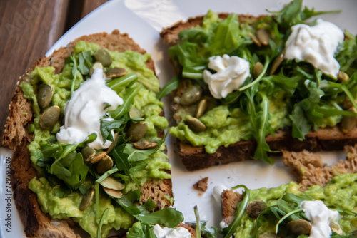 Smashed avocado on Toast with Labneh, Lemon, Parsley, Cheese, Edamame and different dried seeds, sunflower and pumpkin, very healthy and vegan green breakfast made by organic ingredients, healthy food