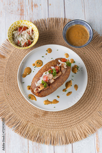 Corviche de verde relleno de carne de chancho en su interior con ensalada de tomate y cebolla y salsas, bocado típico ecuatoriano foto cenital