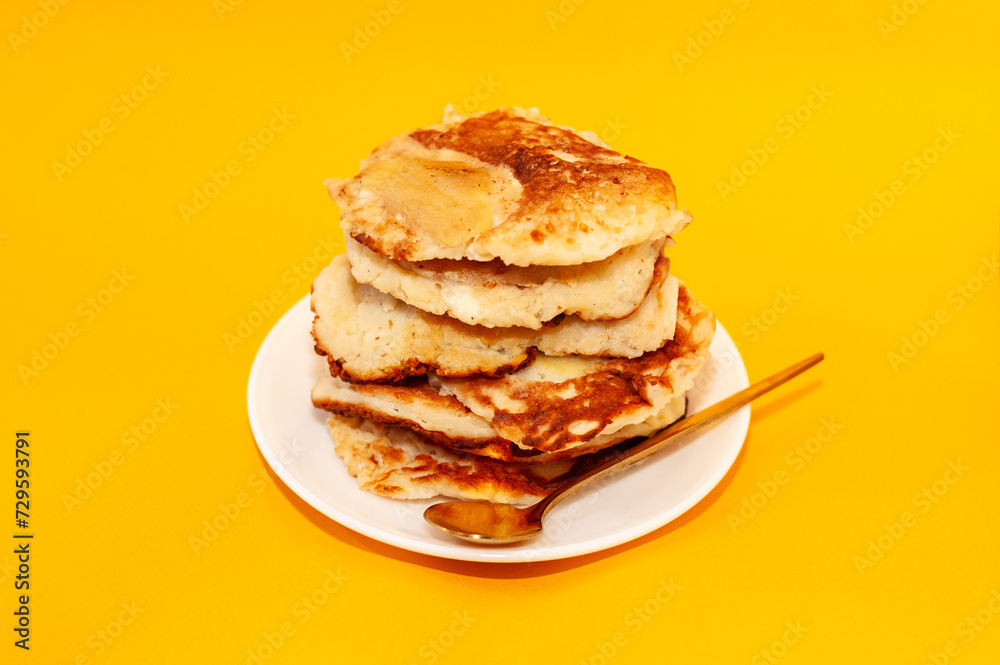 homemade pancakes on a white plate with a golden spoon