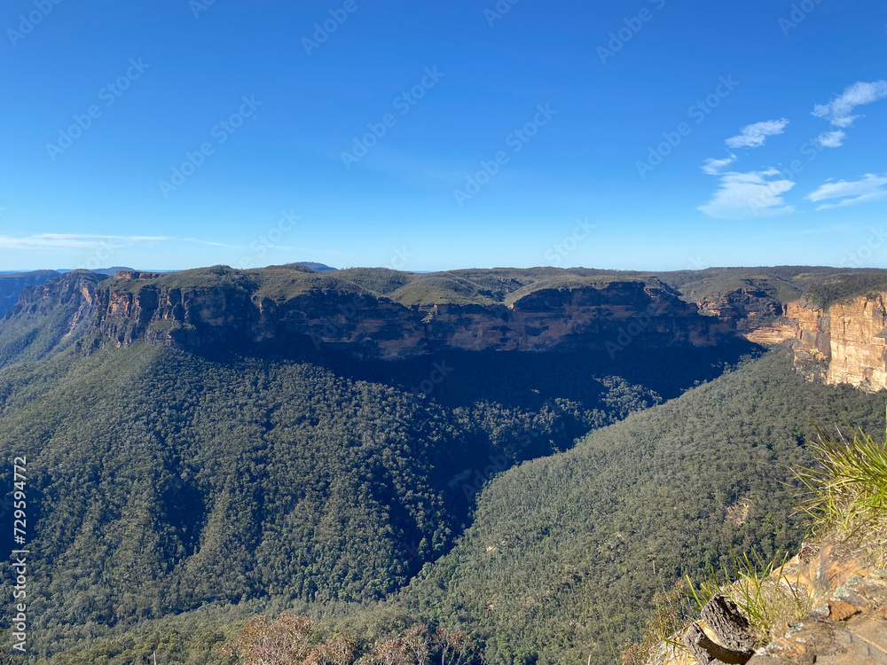Spectacular views from a mountain-top lookout. Green mountains in the horizon. Blue mountains, Australia, NSW. Rock formation at the summit.