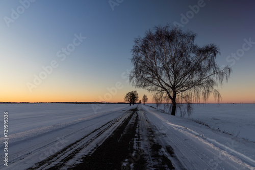 a slippery and dangerous road covered with snow and ice at sunset © rsooll