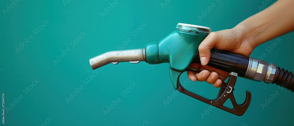 Hand holding a fuel dispenser on a green background - obrazy, fototapety, plakaty 