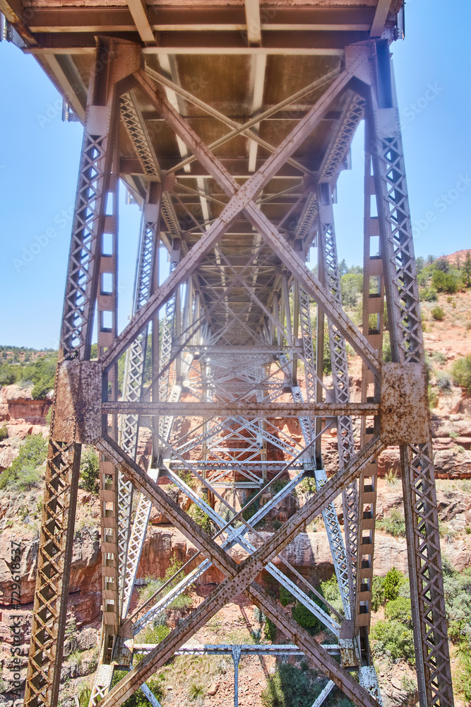 Rusted Steel Truss Bridge Underbelly with Red Rock Background