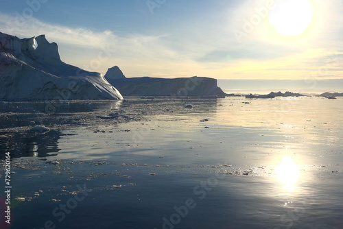Antarctic landscape with snowy mountains, glaciers and icebergs. Landscape of icy shores in Antarctica. Beautiful blue iceberg with mirror reflection floats in ocean. Glaciers of a harsh continent
