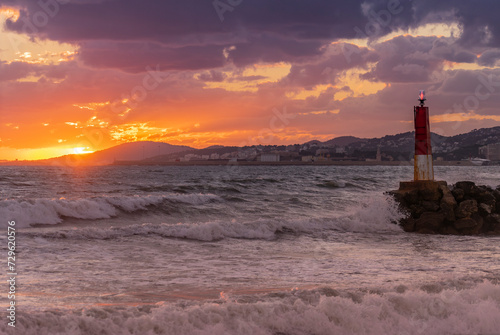 Golden Sunset Casting Warm Hues Over a Coastal Cityscape and Beacon