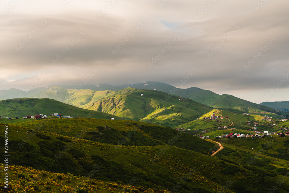 The highland Georgian village of Gomismta at dawn. Georgia travel destination. Mountain landscape of the Caucasus with fresh green meadows and mountain peaks in the background. 