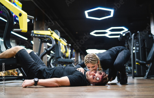 Young woman and man in sportswear doing exercises on the floor in gym.