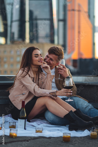 Private wedding for two in casual clothes on a roof top with skyscrapers and urban cityscape on background. Romantic marriage proposal on Saint Valentine's Day. Happy loving beautiful young couple