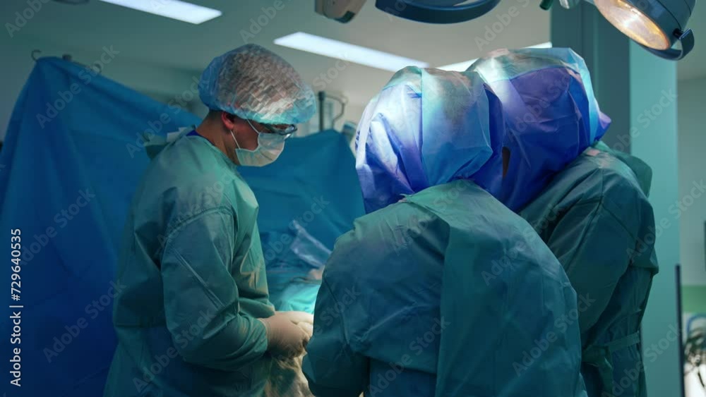 Uniformed medics in protective helmets work at operational table. Trauma surgery in modern hospital. Uniformed medics in protective helmets work at operational table. Trauma surgery in modern hospital.