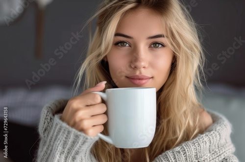 a pretty blonde woman holds a white cup in her hand