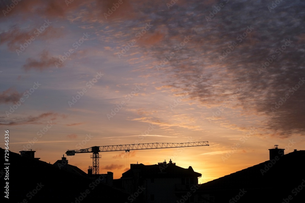 Crane over roofs of buildings in sunrise scenery