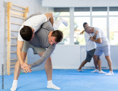 Man with sparring partner in gym during self-defense training  sparring and practicing technique of hip flip