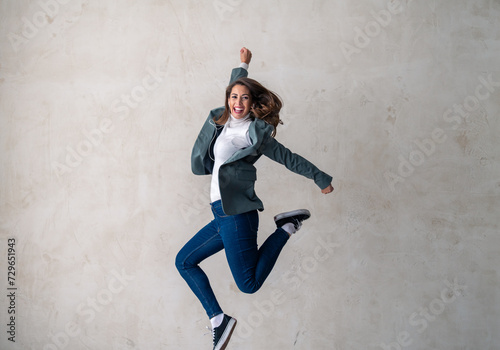Excited young woman moved by the rhythm of the music jumping in mid-air in a studio.
