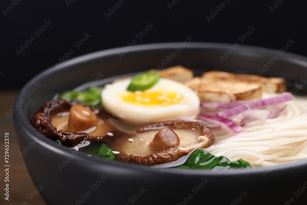 Delicious vegetarian ramen in bowl on table against black background, closeup Delicious vegetarian ramen in bowl on table against black background, closeup