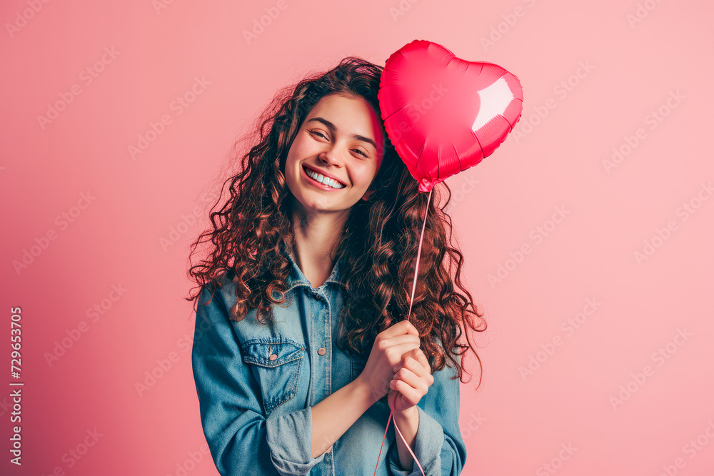 A woman holds a red heart shaped balloon in her hand, showcasing love and affection. A woman holds a red heart shaped balloon in her hand, showcasing love and affection.
