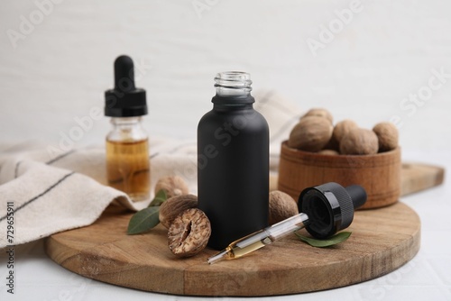 Nutmeg essential oil and nuts on white table