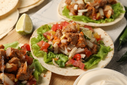 Delicious tacos with vegetables and meat on table, closeup