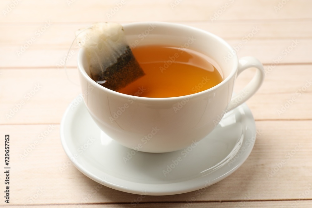 Tea bag in cup on light wooden table, closeup Tea bag in cup on light wooden table, closeup