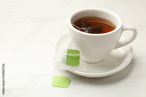 Tea bag in cup on white table, space for text