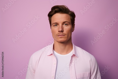 Portrait of a handsome young man in a pink shirt on a purple background.