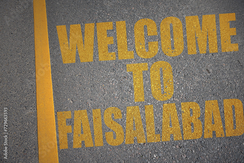 asphalt road with text welcome to Faisalabad near yellow line.