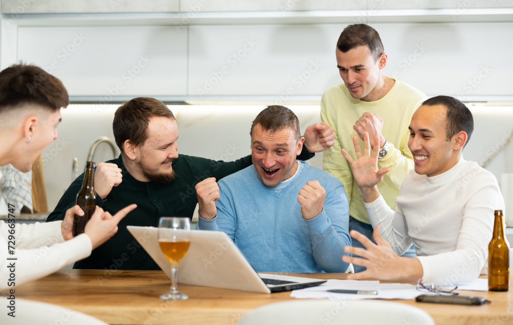 Group of football fans drinking beer and watching football match on a laptop at home