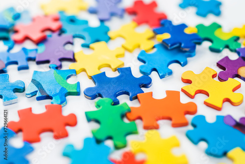 Assorted colorful jigsaw puzzle pieces scattered on a white background  with a focus on a central yellow piece.