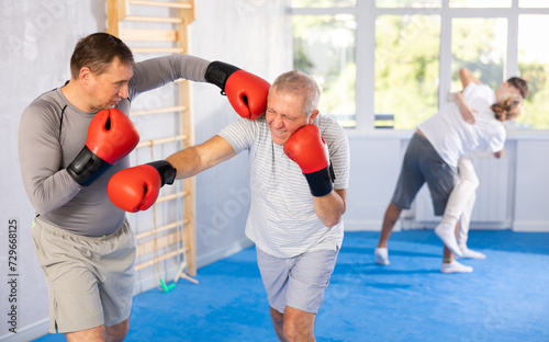 Boxing fight - elderly man learning to box in sparring with trainer © JackF